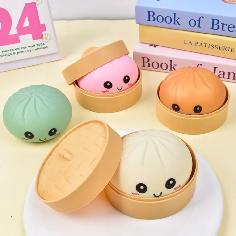 Boutique Planete Jouets France - Squishy Dumpling Pastel avec Panier Vapeur – 4 Couleurs 3 Quatre squishies dumpling pastel avec panier devant des livres - Planete Jouets France